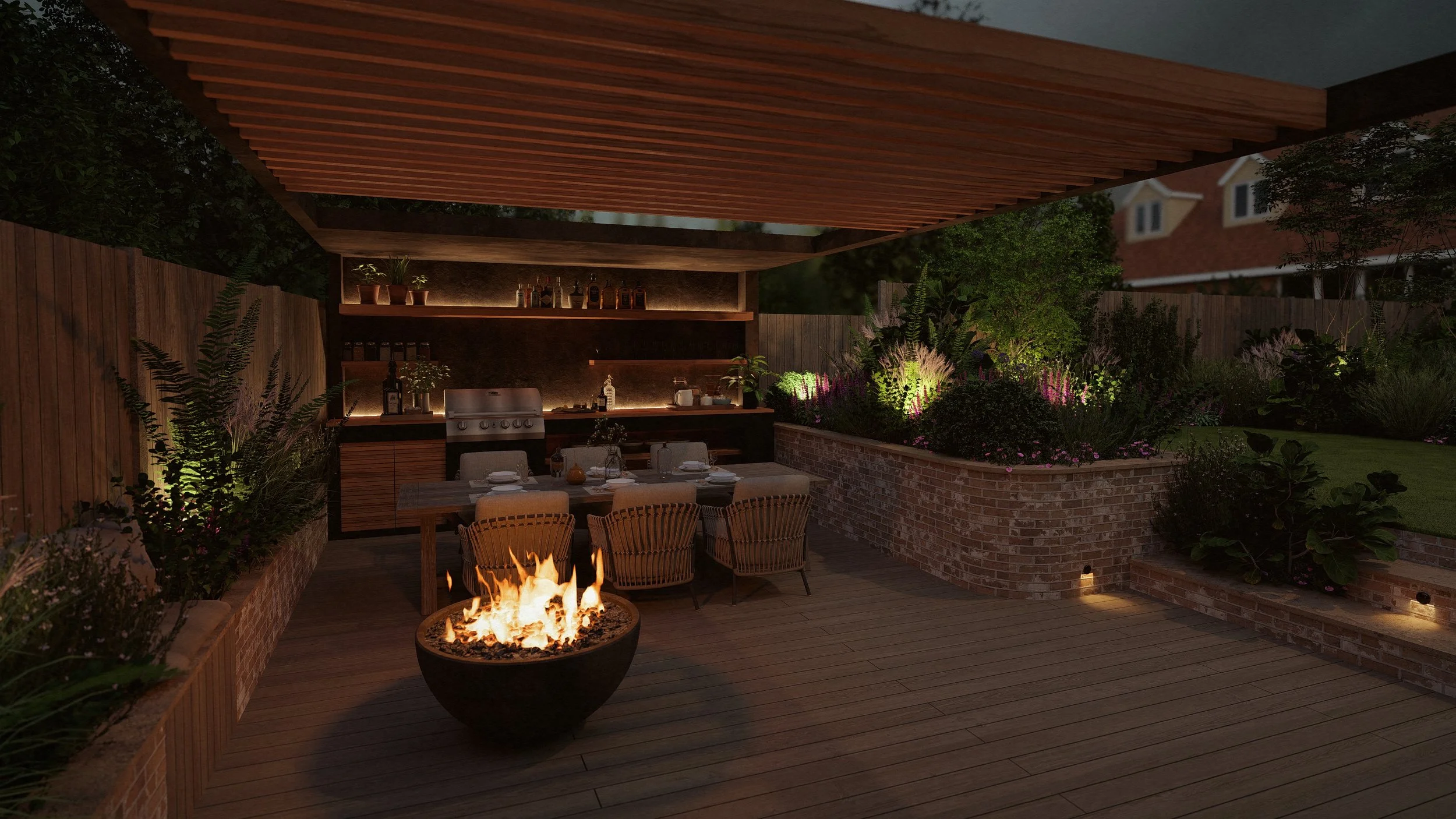 Outdoor patio space with a fire pit, dining table with chairs, and a built-in outdoor kitchen area surrounded by garden plants and trees at night.