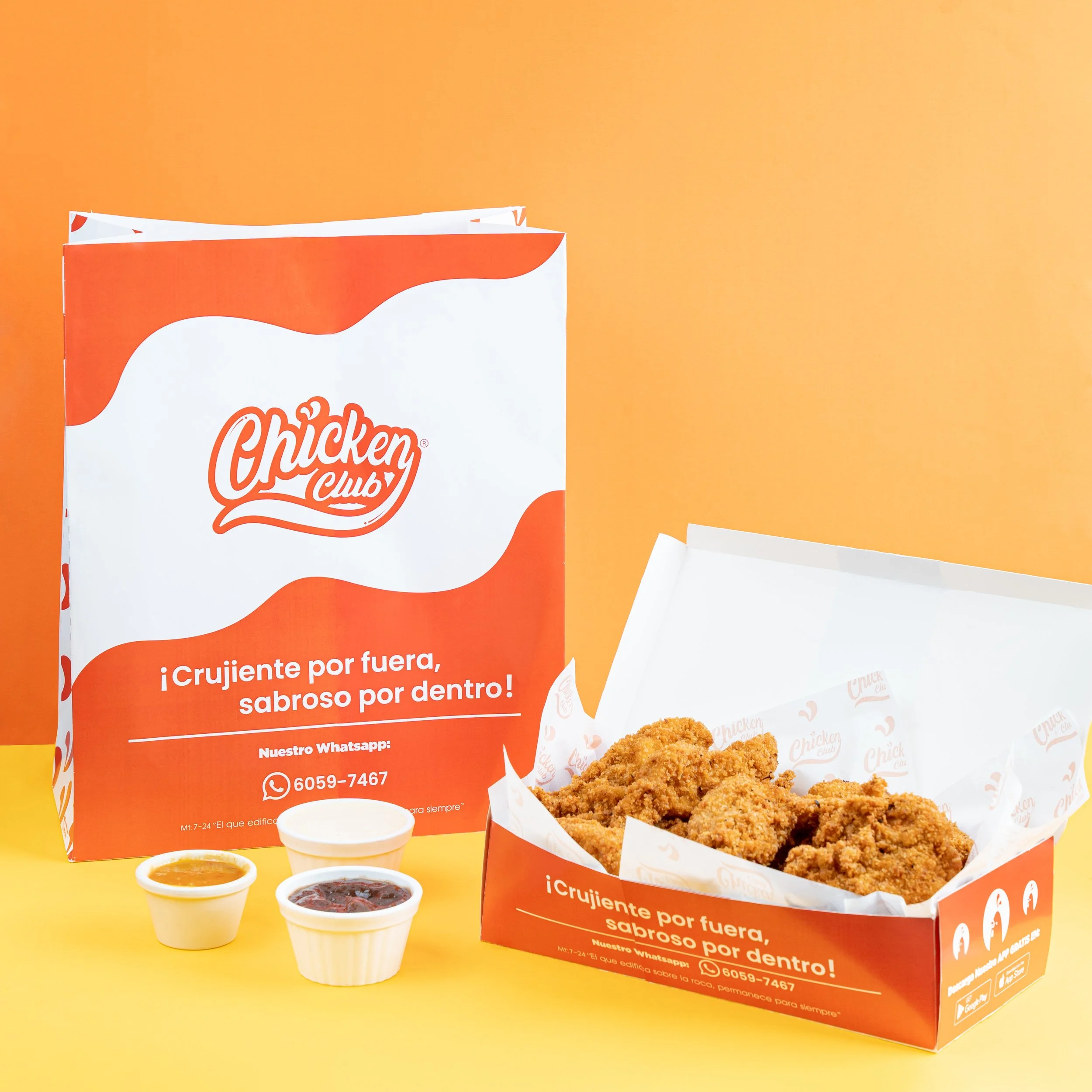 Cajita con pollo frito crujiente y salsas al lado, logotipo de Chicken Club en la caja y cartel con texto en español.