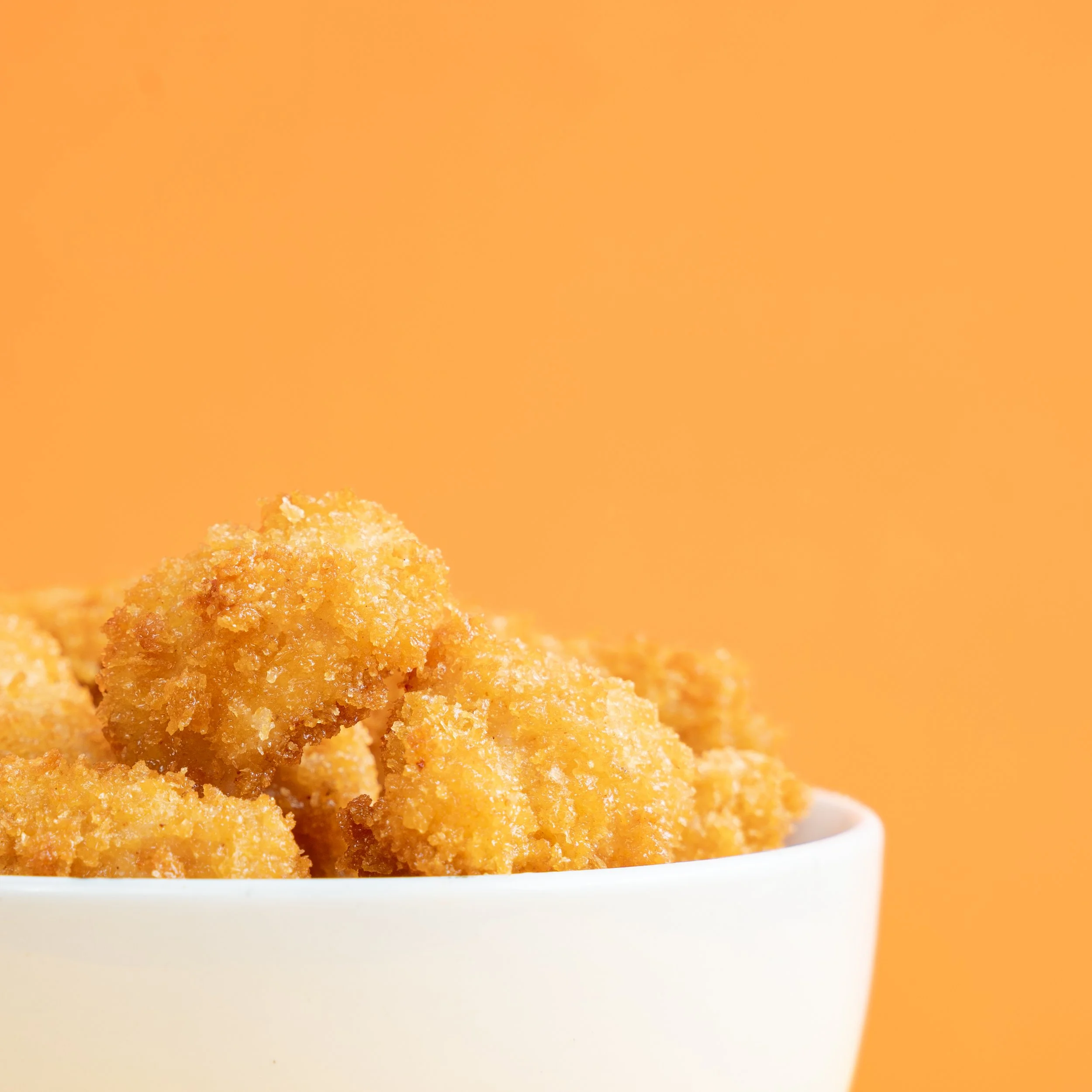 Tazones con pedazos de pollo frito en un fondo naranja
