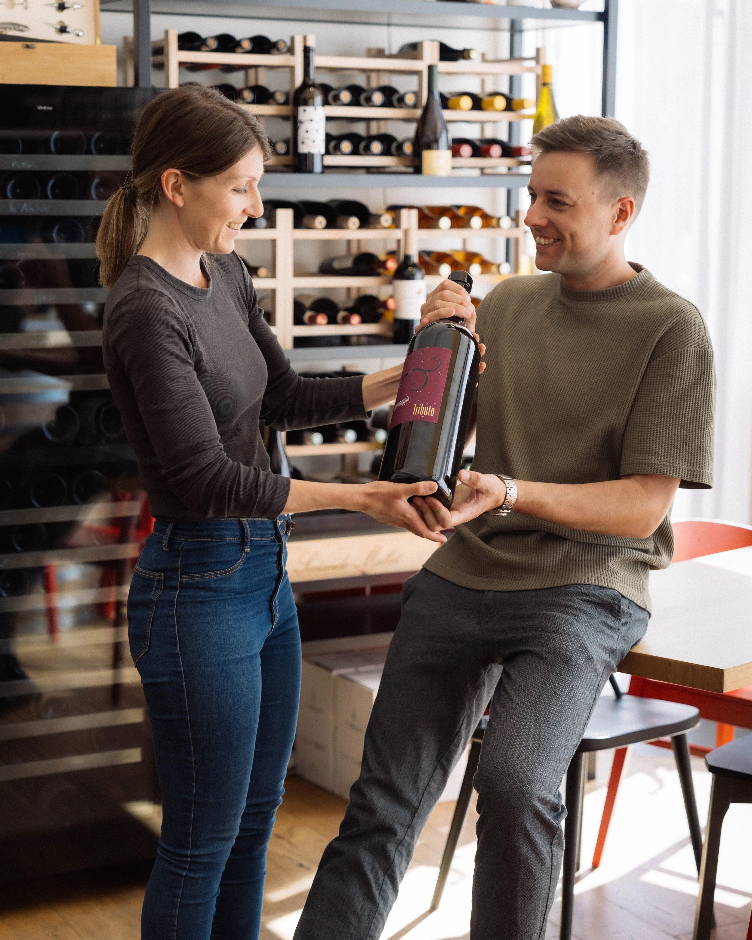Clara & Mathias holding a large bottle of wine