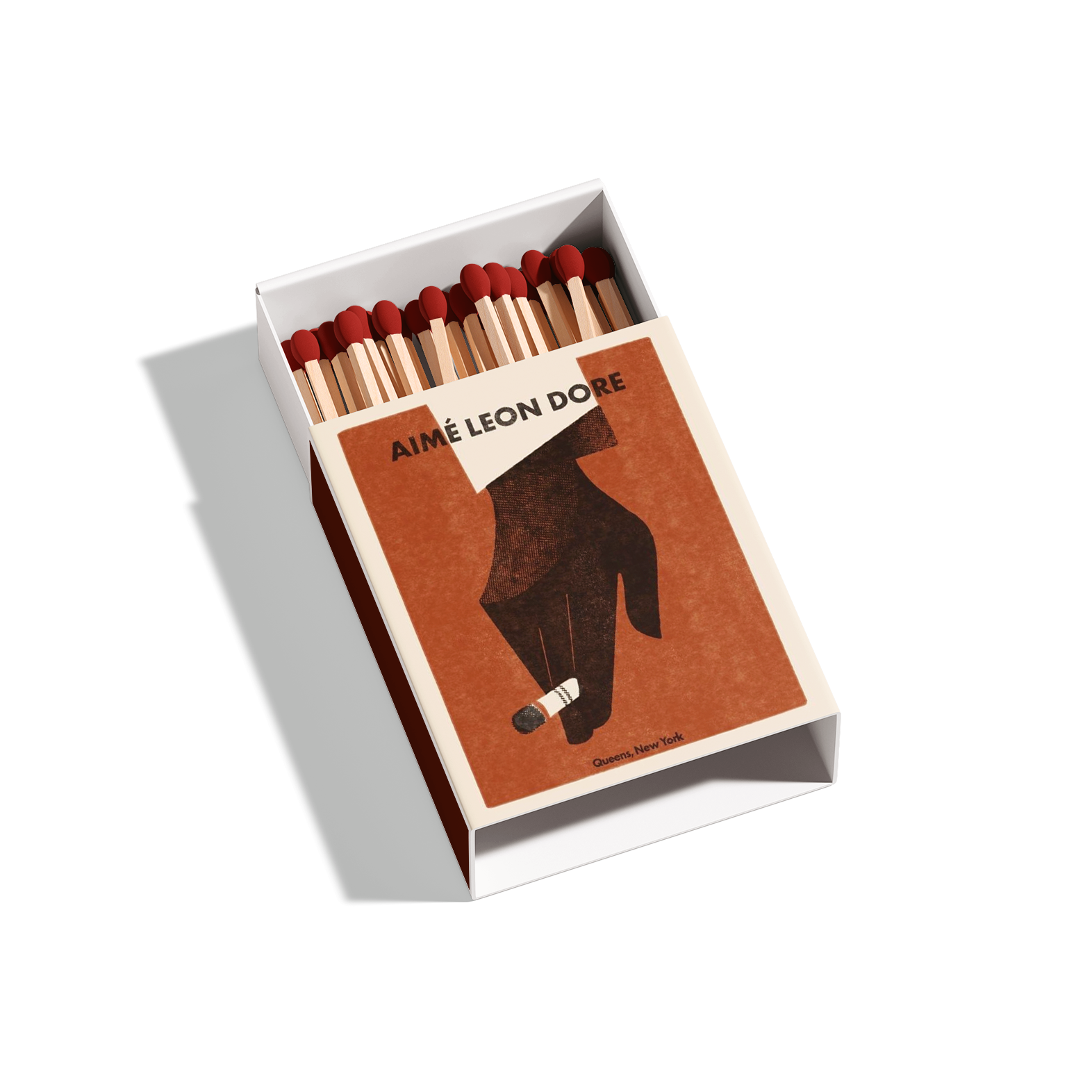 A box of matches with a cover displaying an artistic illustration of a woman walking with a cigarette, titled 'AIME LEON DORE,' with a location noted as Queens, New York.