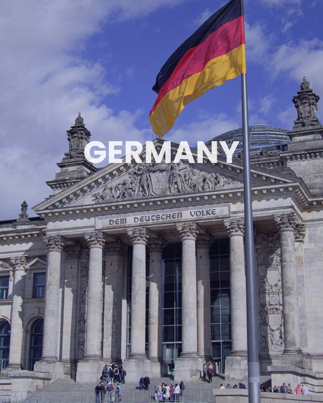 Germany flag in front of a grand neoclassical building with large columns and intricate stone carvings, people gathered sitting and standing near steps.