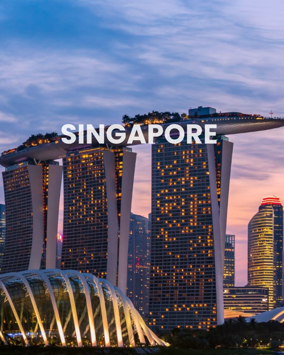Night view of the Marina Bay Sands hotel in Singapore with brightly lit windows and the SkyPark on top.