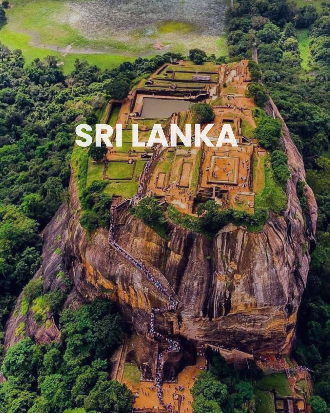 Aerial view of Sigiriya, ancient fortress and palace ruins built on a large rock formation in Sri Lanka, surrounded by dense jungle.