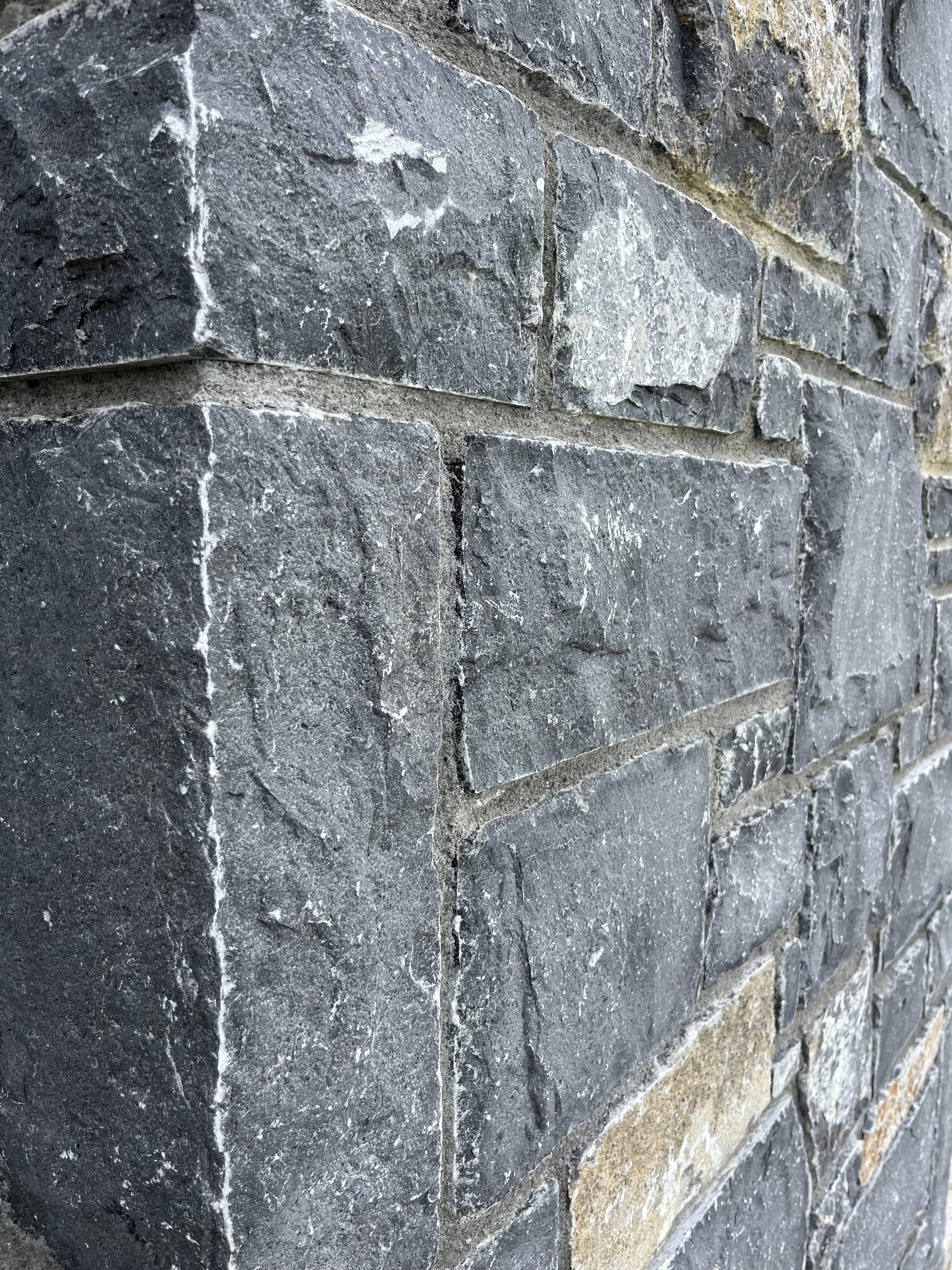 Close-up of a brick wall with dark gray and beige stones arranged in a pattern.