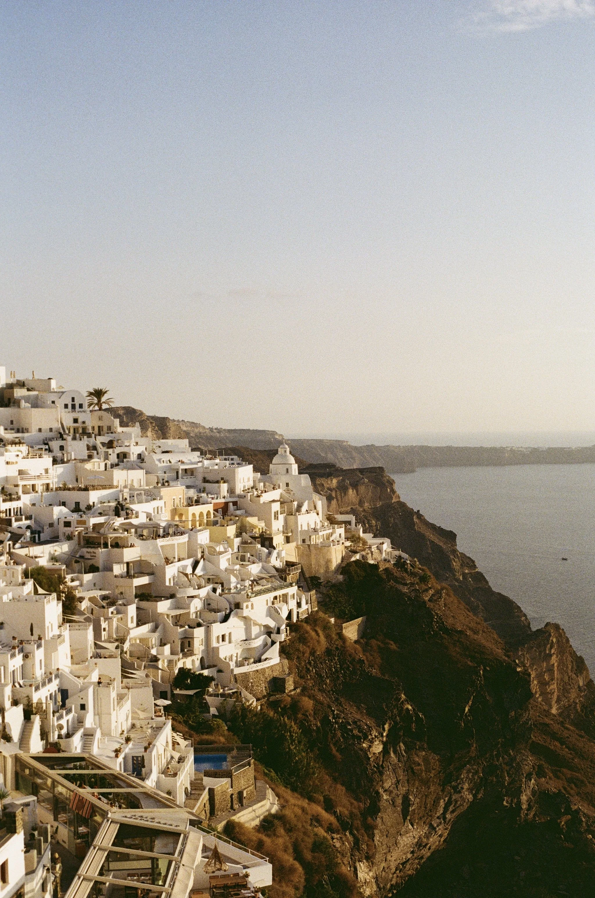 White buildings on cliffs overlooking the sea during sunset at Santorini, Greece.