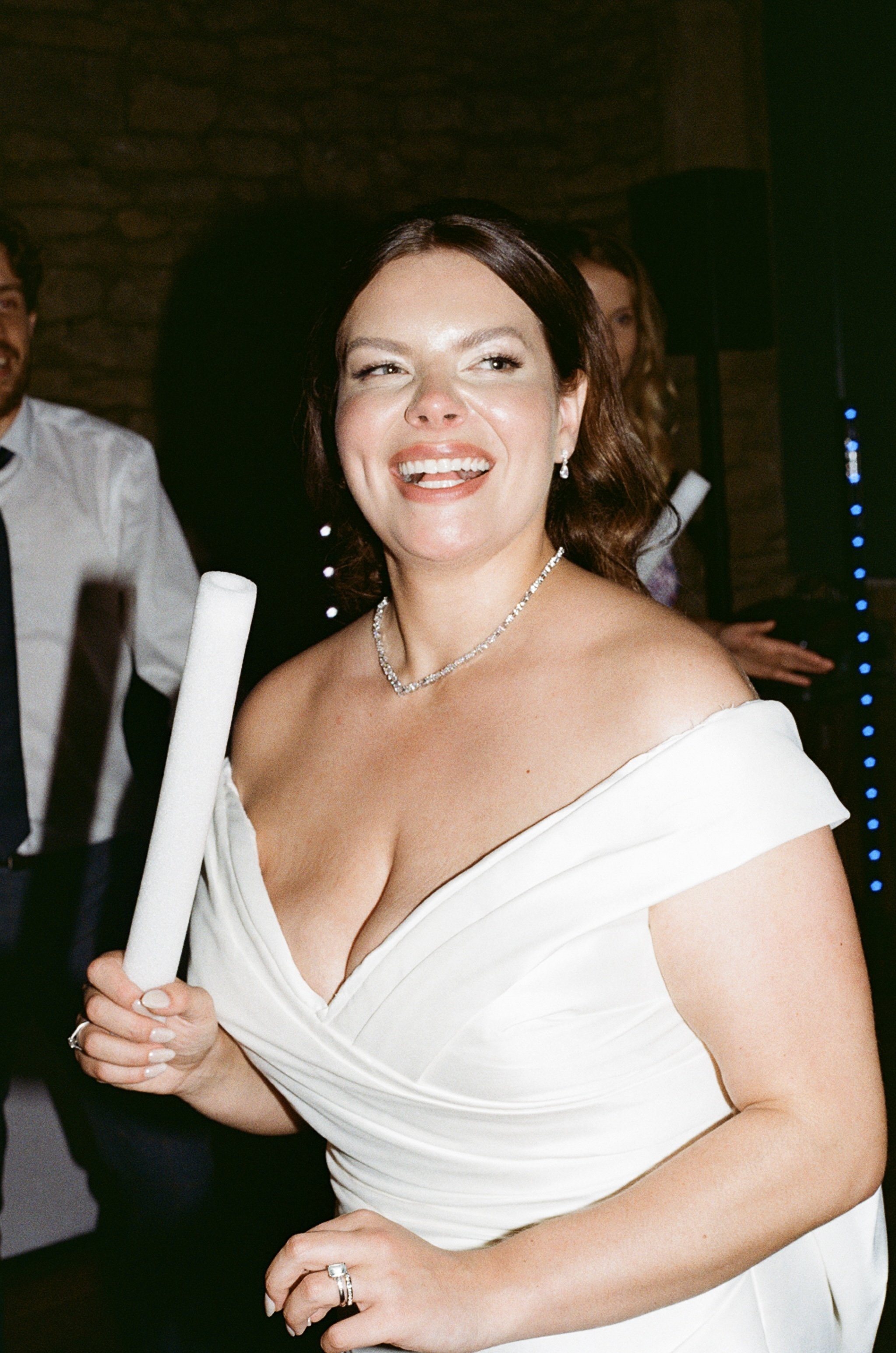 Woman in a white dress holding a rolled napkin at a celebration or wedding.