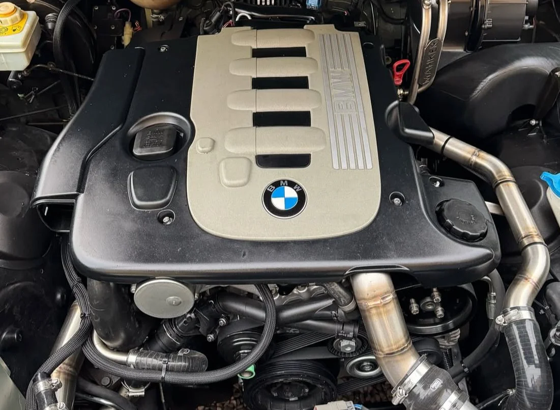 BMW M57 Defender engine. engine with black and silver components and BMW logo in the center.