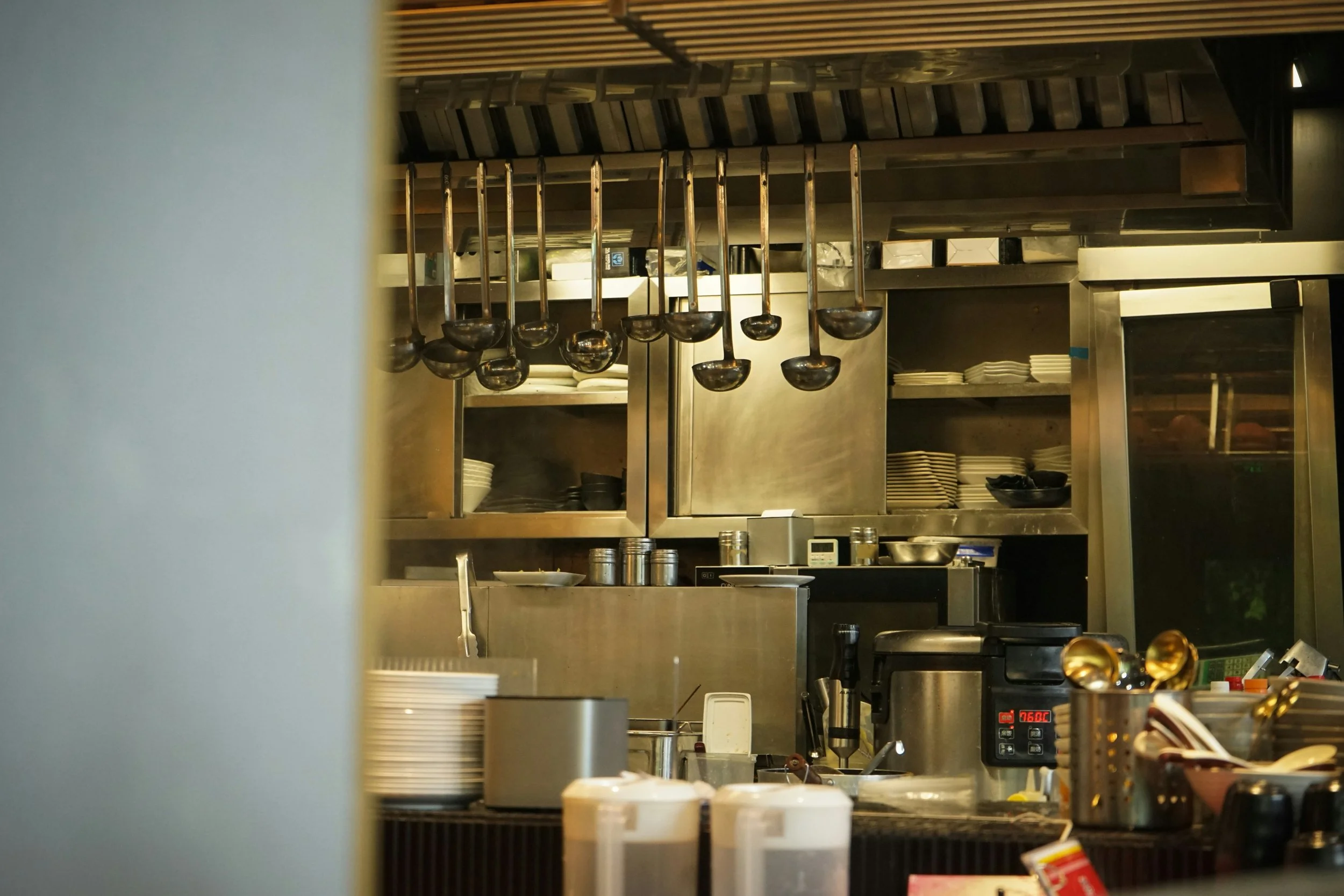“Professional restaurant kitchen with organised equipment and ladles hanging above the cooking line.”