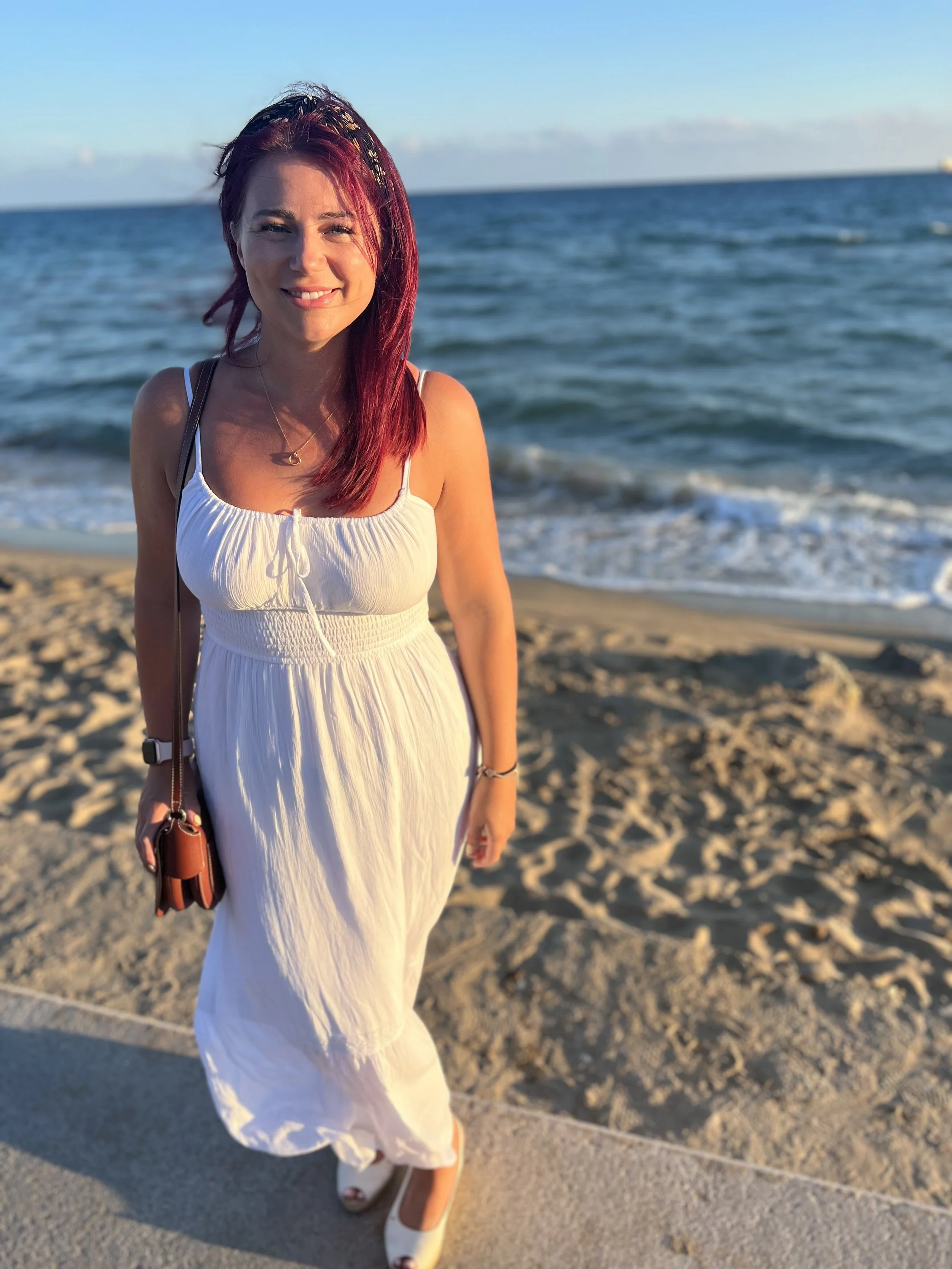 woman in white dress stands on a the beach