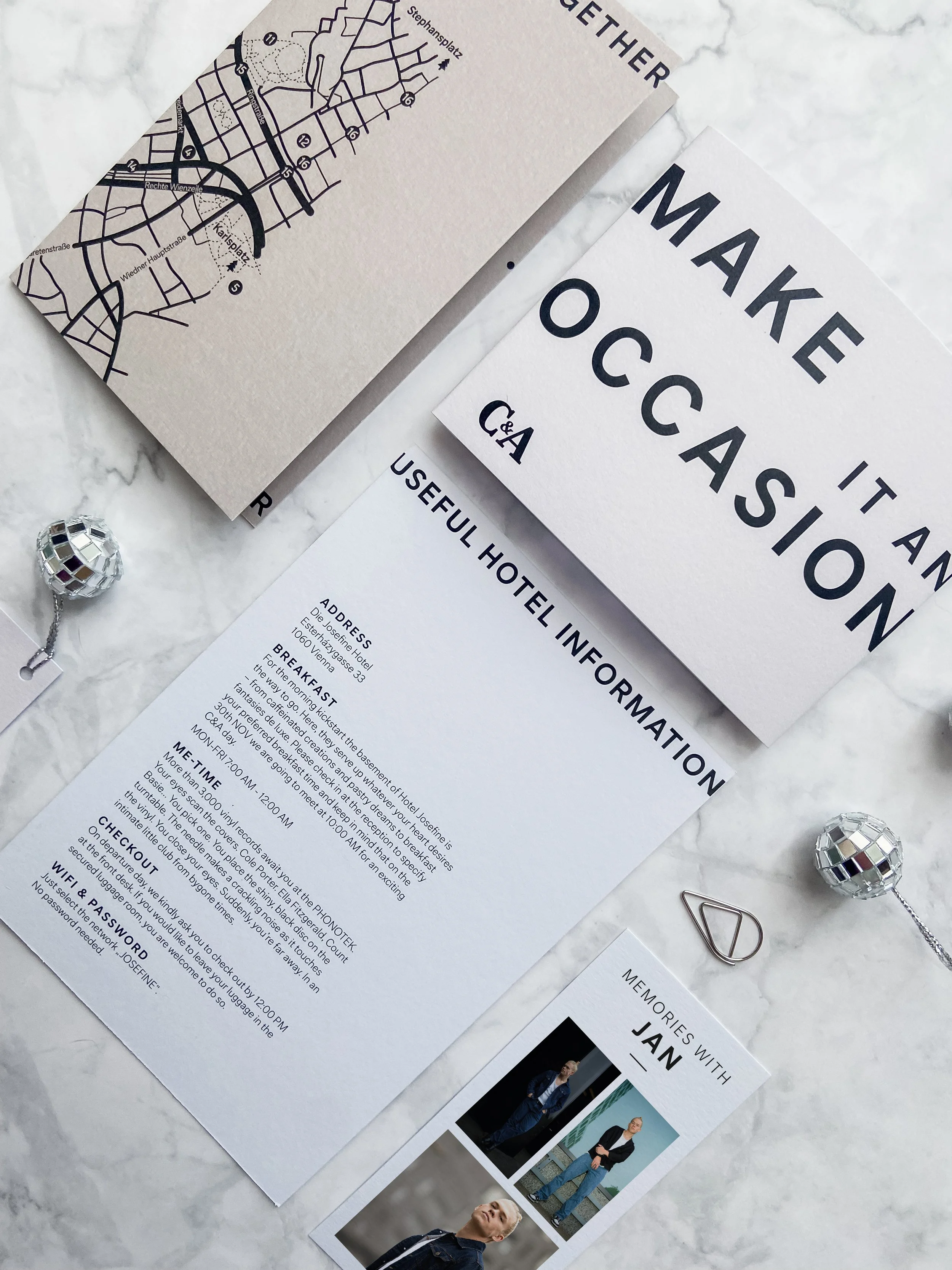 Reiseunterlagen und Info-Blätter für einen Aufenthalt bei einem Influencer Event in Wien, inklusive Karte, Hoteladresse und Erinnerungen an eine Person namens Jan, auf einem weißen Marmortisch.