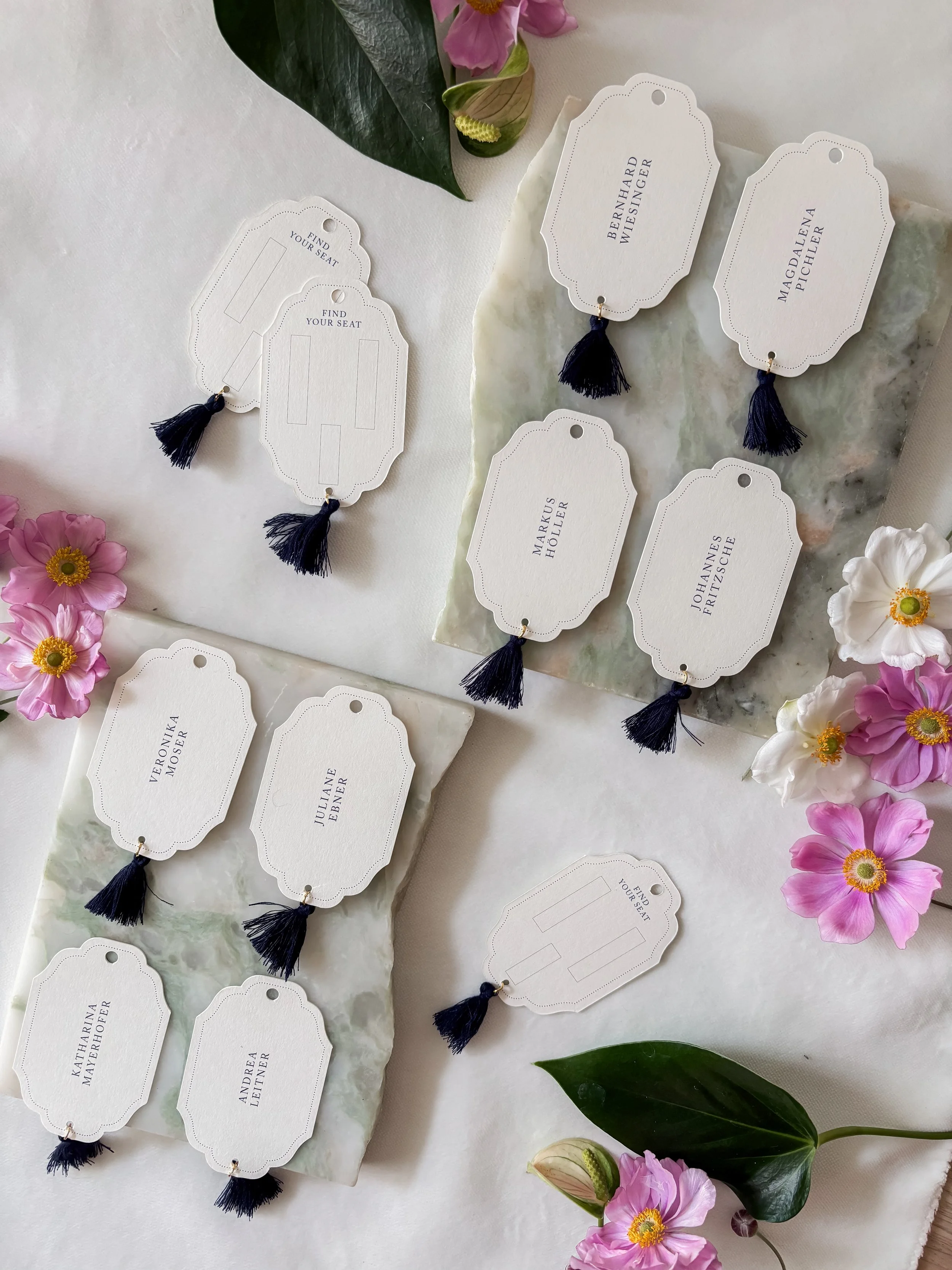 Tischdekoration mit Namensschilden und Blumen in Pastellfarben, verwendet für eine Veranstaltung wie eine Hochzeit.