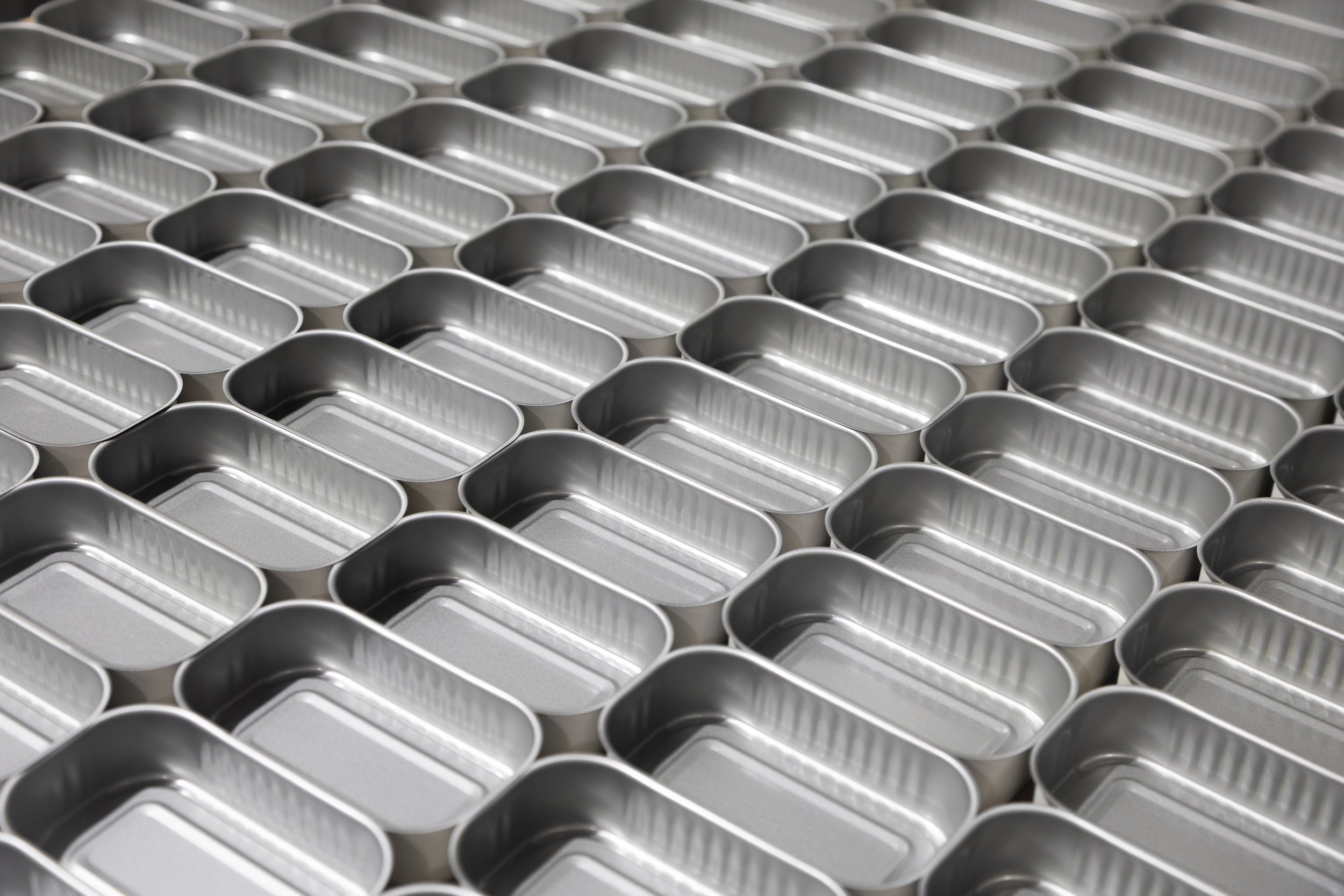 Multiple empty silver rectangular metal cans arranged in a grid pattern.