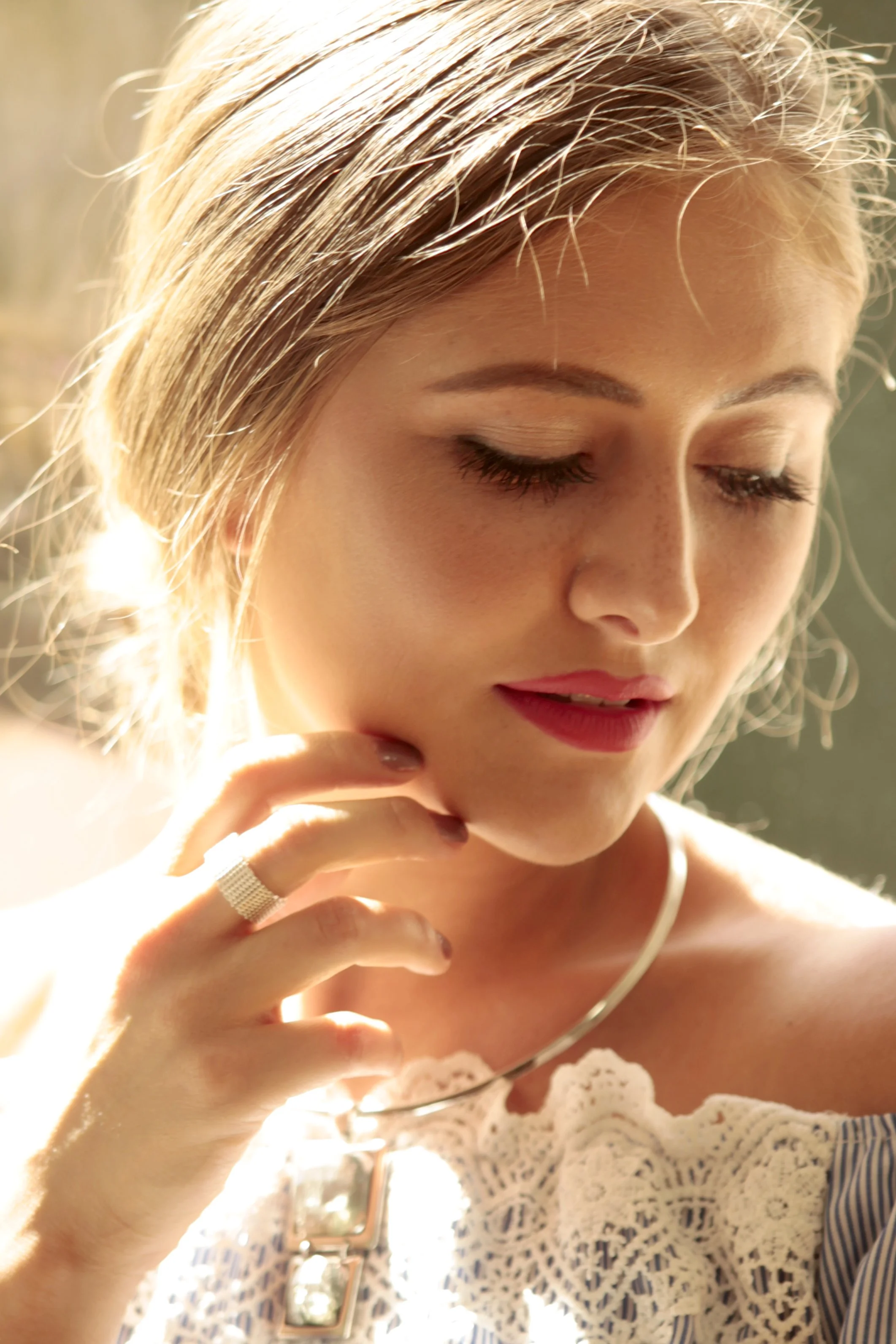 Nahaufnahme einer Frau mit blonden Haaren, die Kleidung im Detail trägt, bei Sonnenschein.