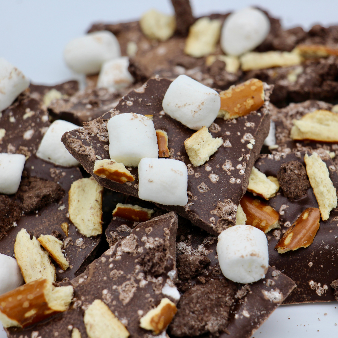 Close-up of broken pieces of chocolate bark with mini marshmallows, pretzels, and cookie crumbs.