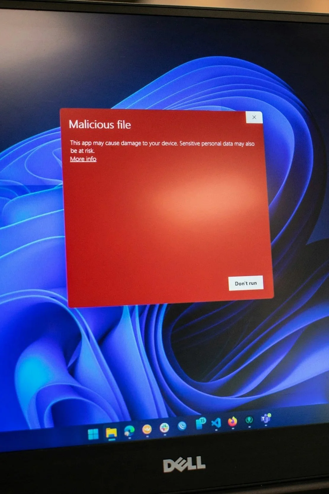 A computer screen displays a red warning box titled 'Malicious file' with a message warning about potential damage and sensitive data risks, and a button labeled 'Don't run'.