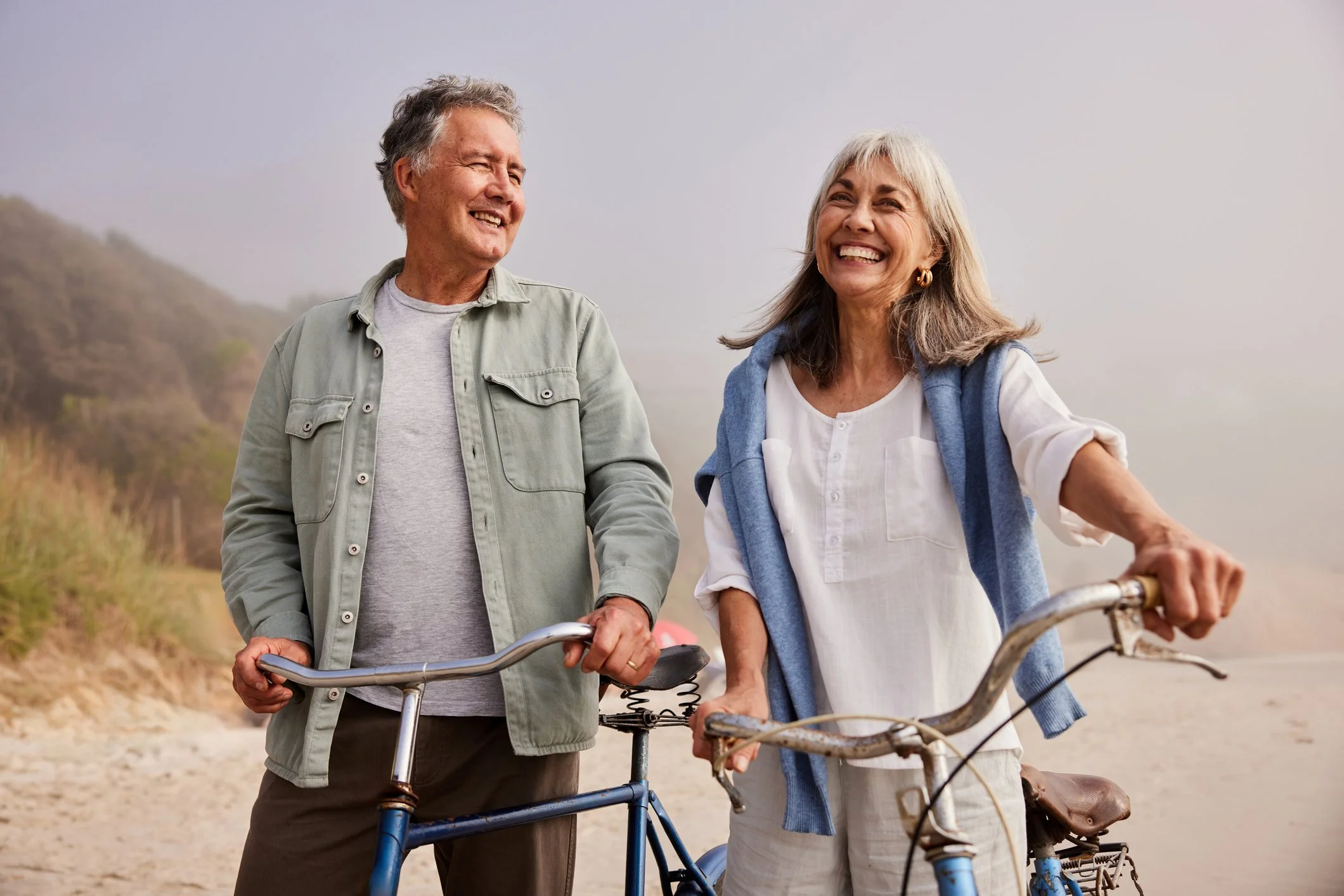 Man and woman laughing and enjoying life riding bicycles on the beach