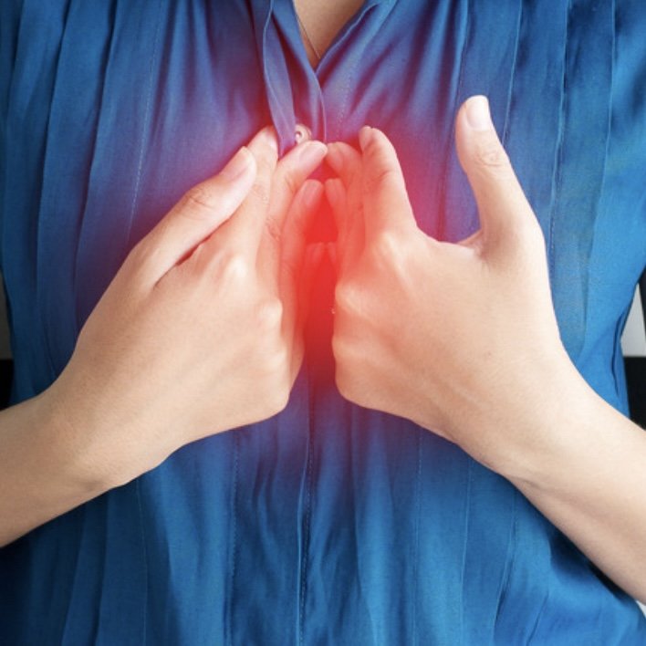 Woman clutching her chest, illustrating acid reflux symptoms linked to bronchiectasis