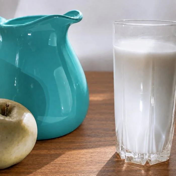 Aqua pitcher, glass of milk and green apple on a table
