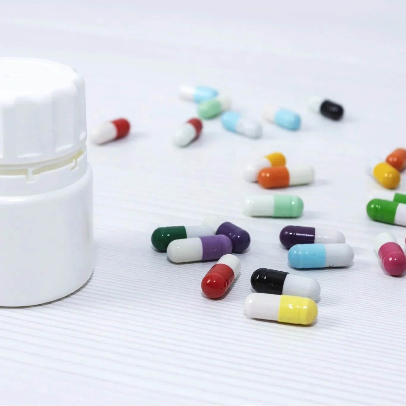 colorful pills on white table with supplement container