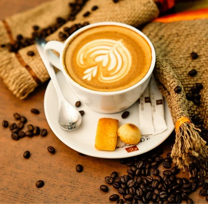 coffee in a white cup with to cookies