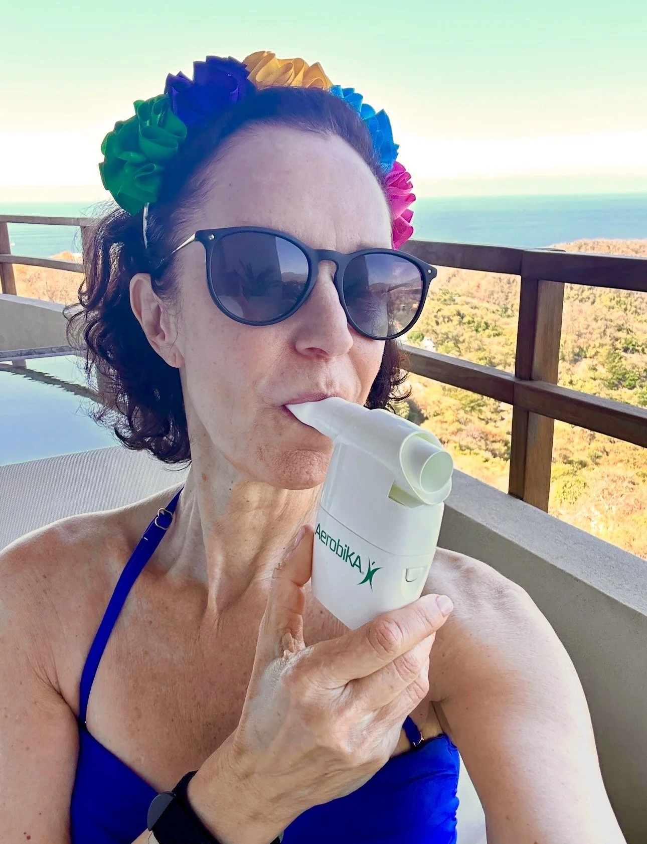 Linda Esposito on balcony doing airway clearance with an Aerobika OPEP device from Monaghan Medical
