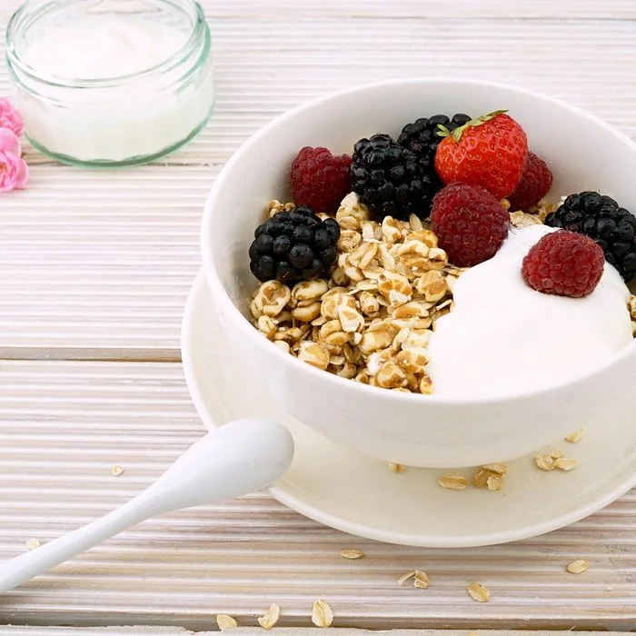 white bowl with yogurt, granola and berries