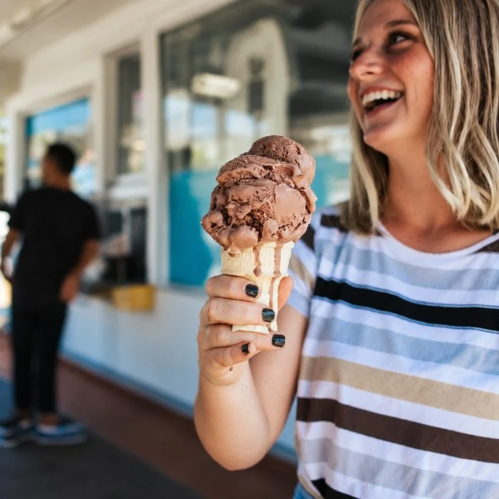 laughing woman holding chocolate ice cream cone