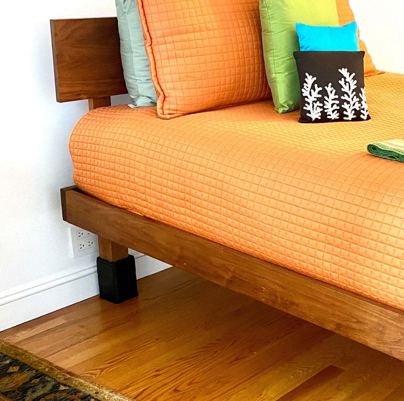 bed with orange bedspread and risers under the head of the bed to prevent acid reflux