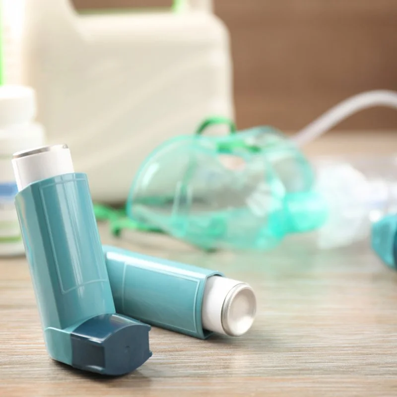 Albuterol rescue inhalers with a nebulizer mask in the background, used to treat bronchiectasis flare-ups