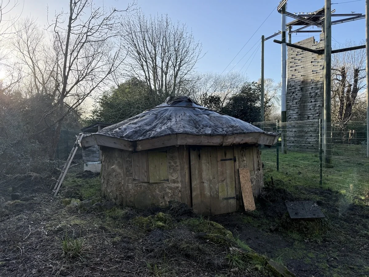 Our roundhouse, a mud and wood structure is missing part of it's roof halfway through replacement.