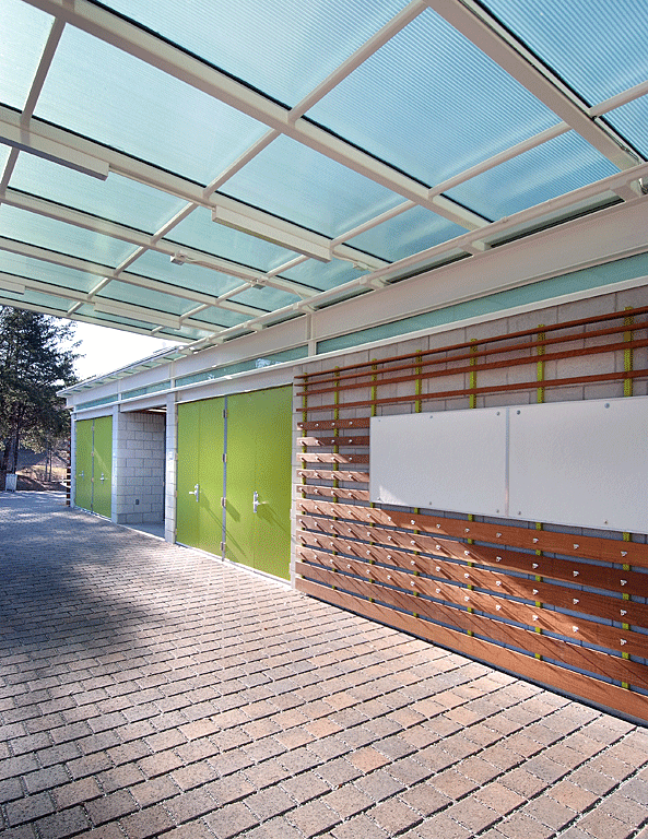 Support pavilion with green doors and roof filtering natural light