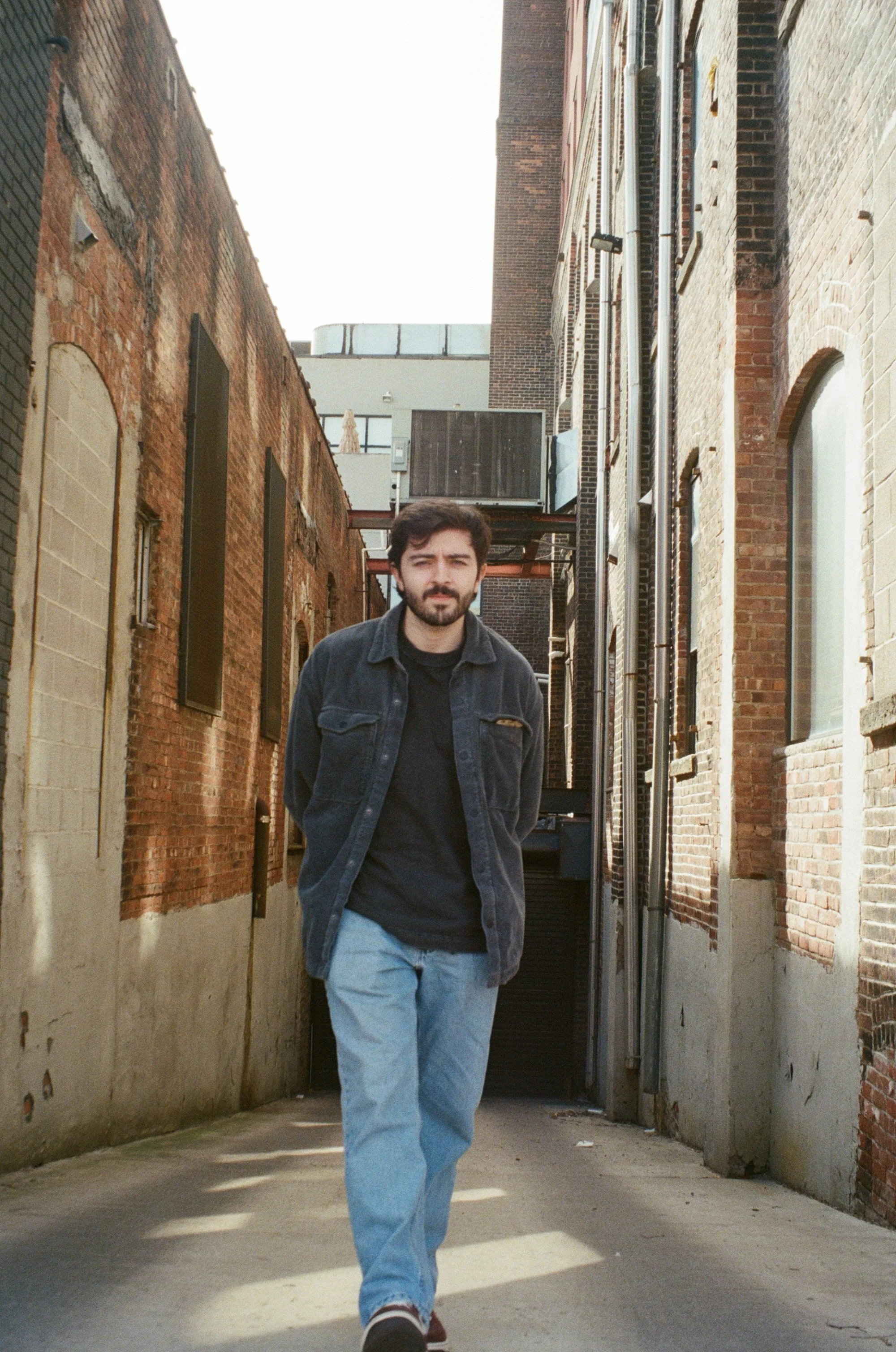 Scenic view of a lake surrounded by green rolling hills and mountains under a cloudy sky.