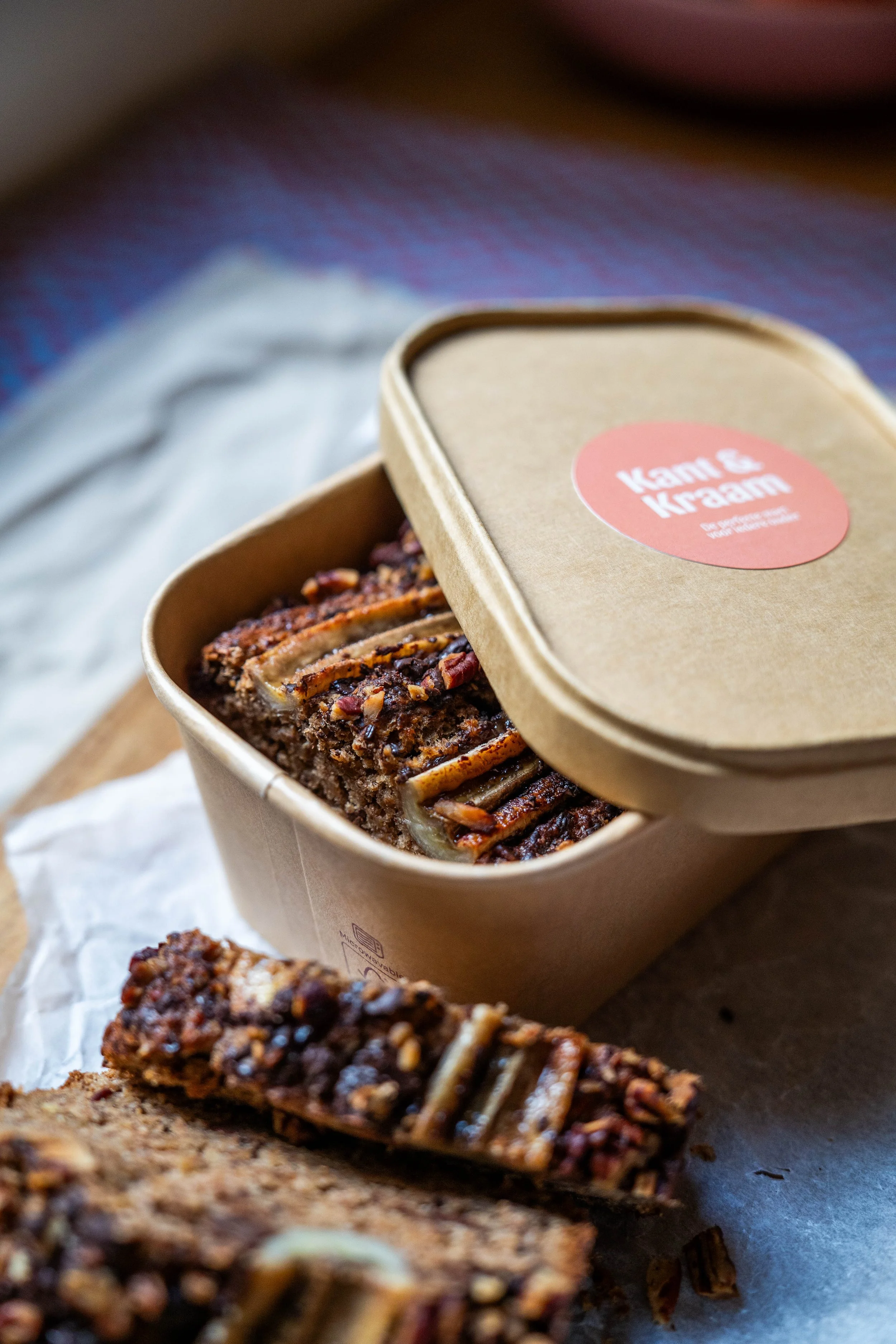 Een doos met een slagroomgebak met noten en karamel en een stuk ervan uitgesneden op een wit vel papier.