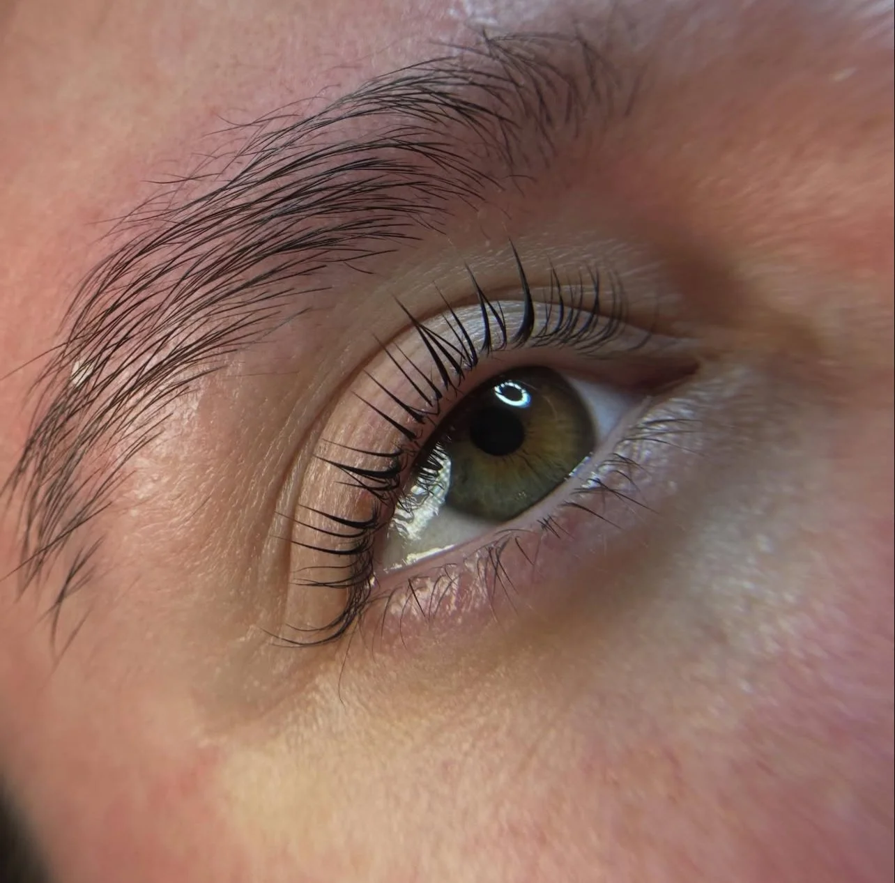 Close-up of a human eye with hazel iris, detailed eyelashes, and light skin.
