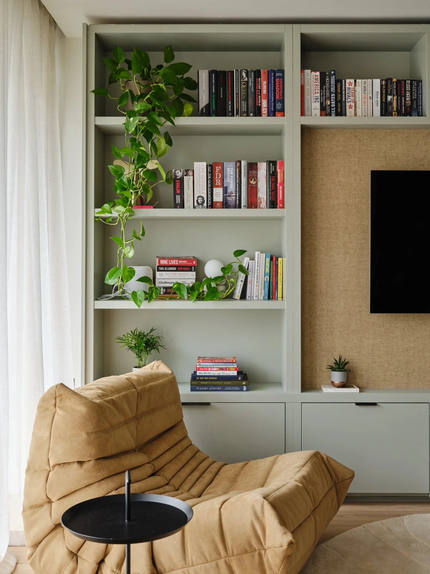 Bespoke living room shelving with integrated cabinetry, books and indoor plants in a contemporary Fulham apartment.