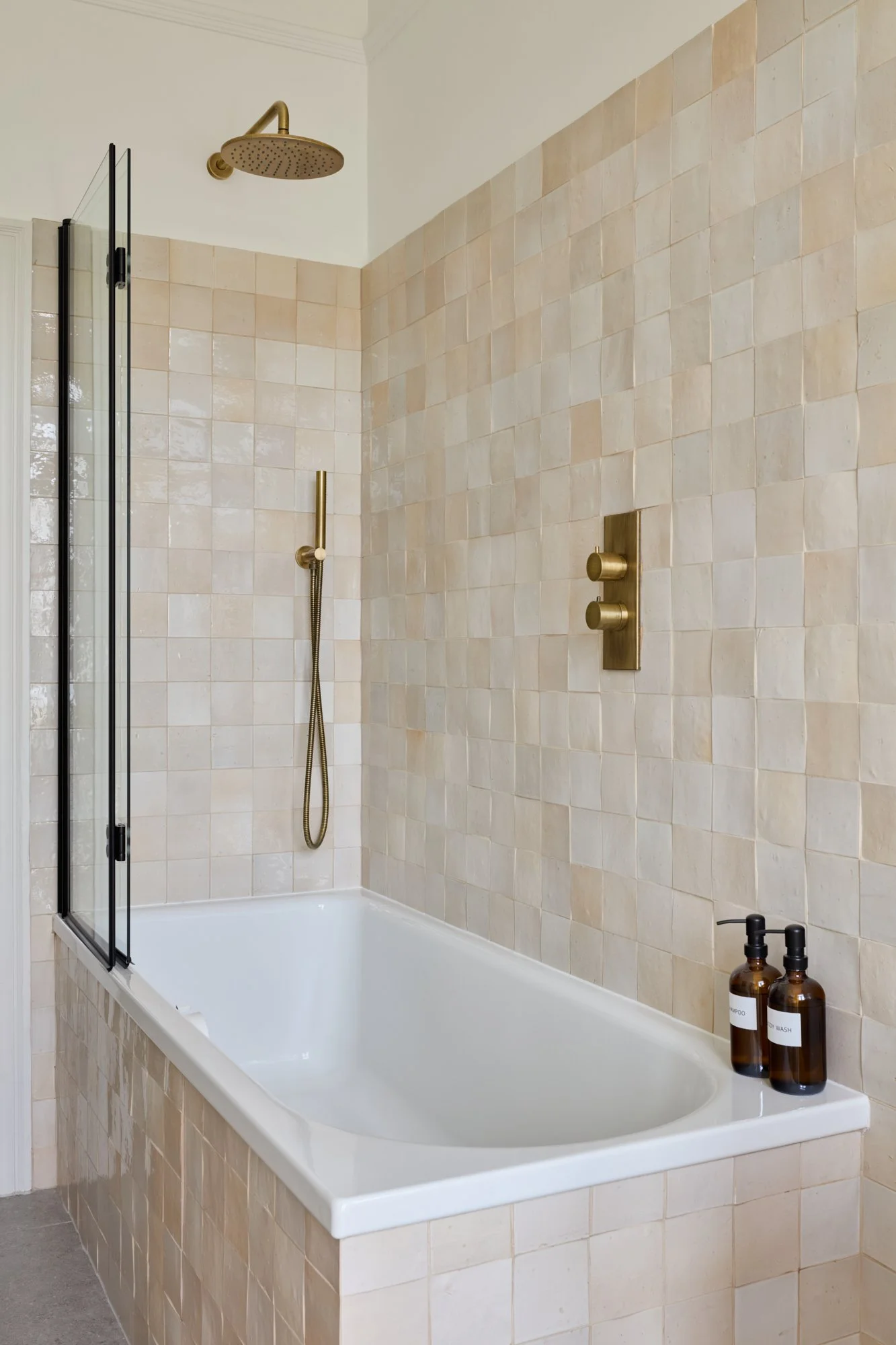 Tranquil bathroom interior featuring artisanal zellige tiles and aged brass fixtures for a touch of warmth and luxury. Elegant shower and bath area.