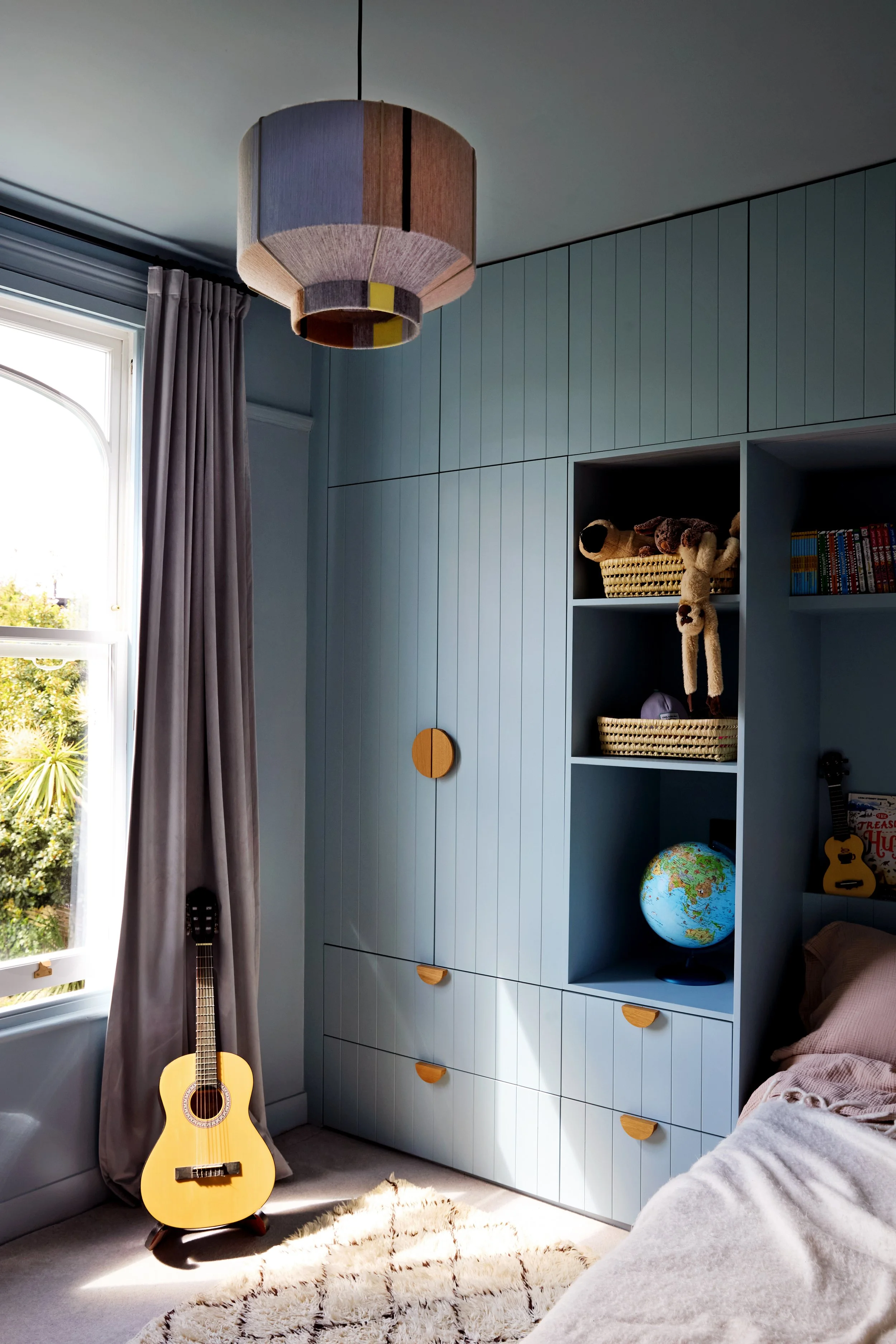 Floor-to-ceiling storage and open shelving provide ample space for clothes, books and treasured possessions without overwhelming the room.