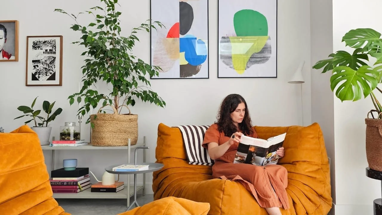 Togo sofa in living room corner, surrounded with art and plants