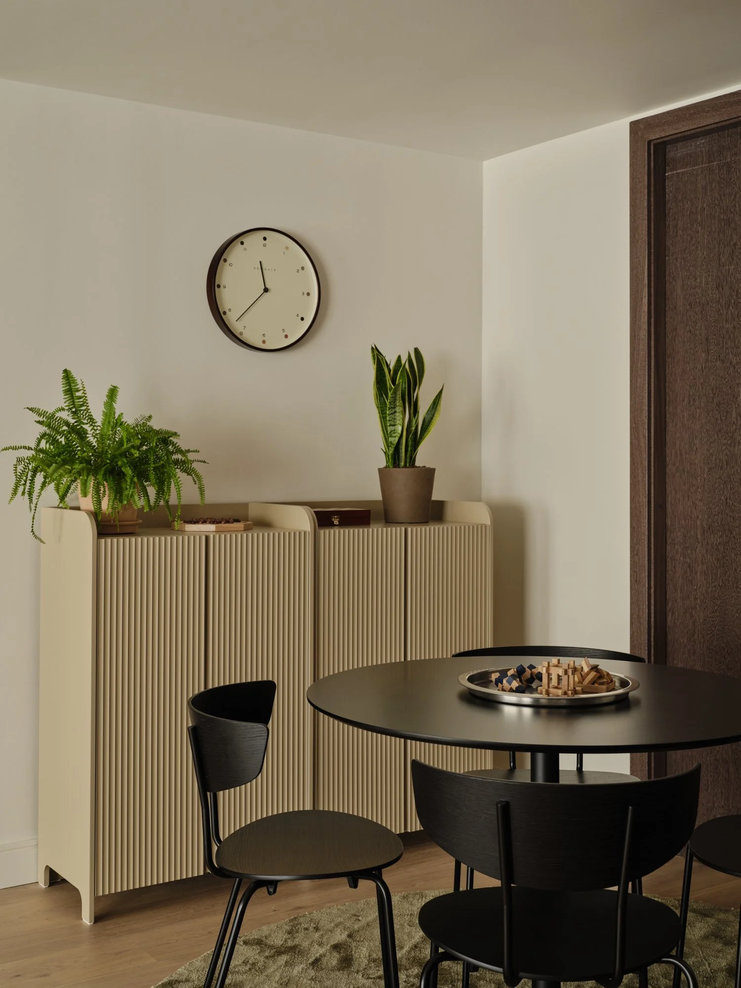 Family game corner featuring ribbed cabinetry, round table and soft textures in a modern West London home.