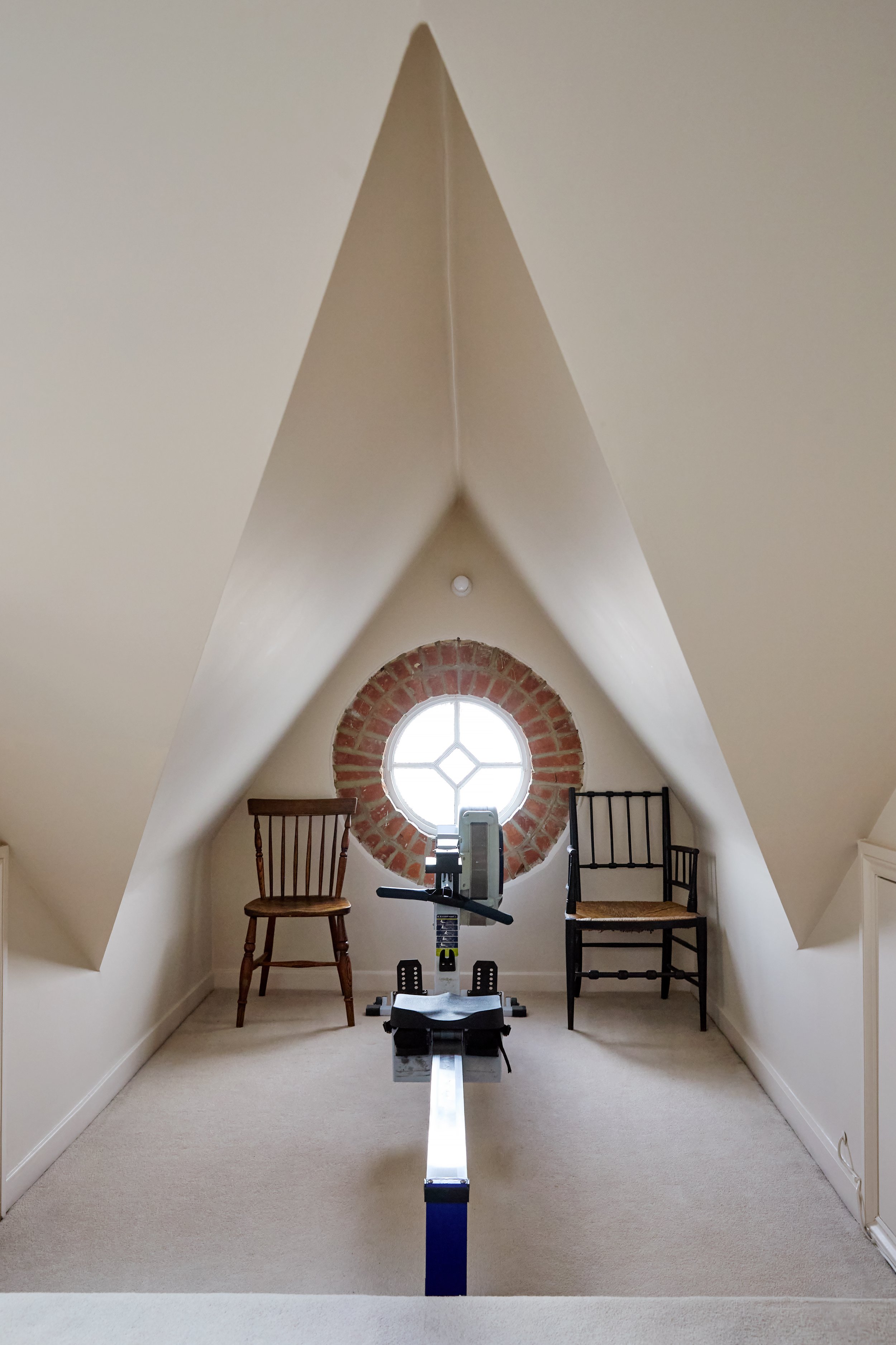 The loft now accommodates a dedicated fitness space, supporting the family's changing needs while making full use of the available footprint. Including this rowing station under the eaves.