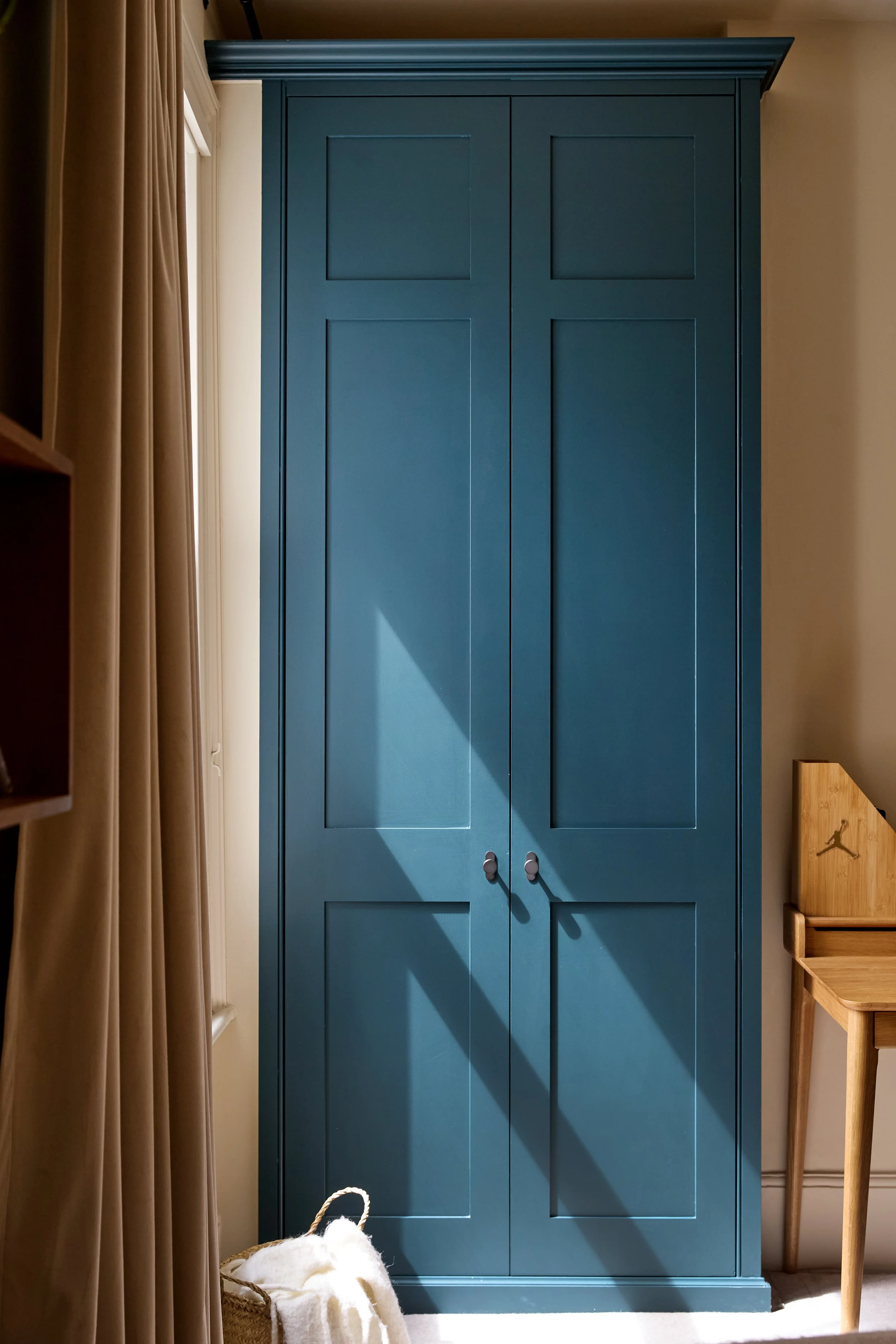Generous storage solutions help keep the room organised while allowing space for books, collections and personal displays.