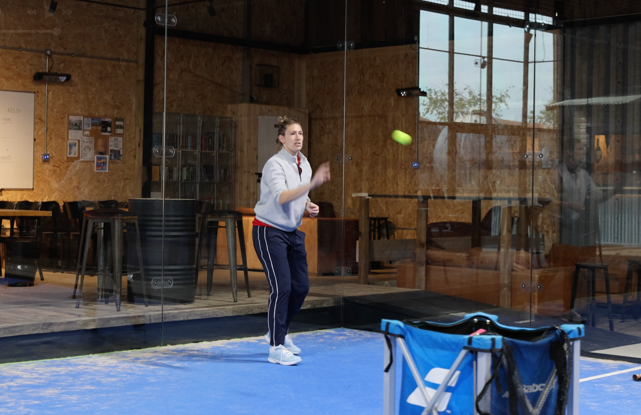 Coach playing padel on blue court with yellow ball