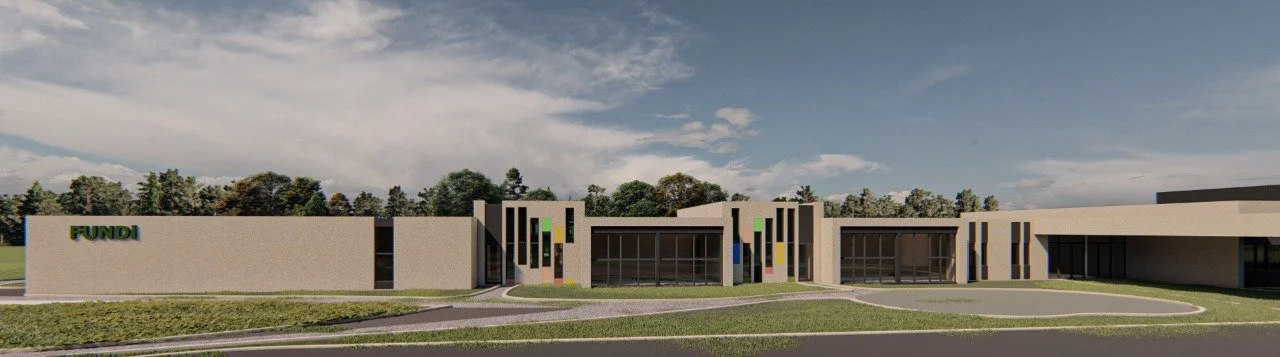 Vista frontal de un edificio moderno con el rótulo 'FUNDI' en la esquina izquierda, rodeado de césped, árboles y un cielo parcialmente nublado.