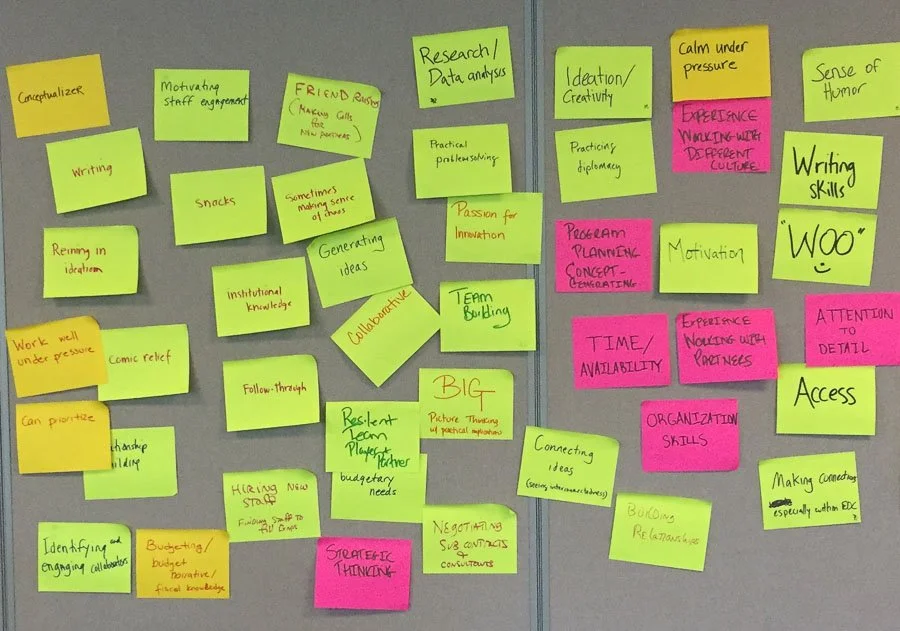 A collection of colorful sticky notes arranged on a gray surface, with handwritten ideas and keywords related to team building, creativity, and project planning.