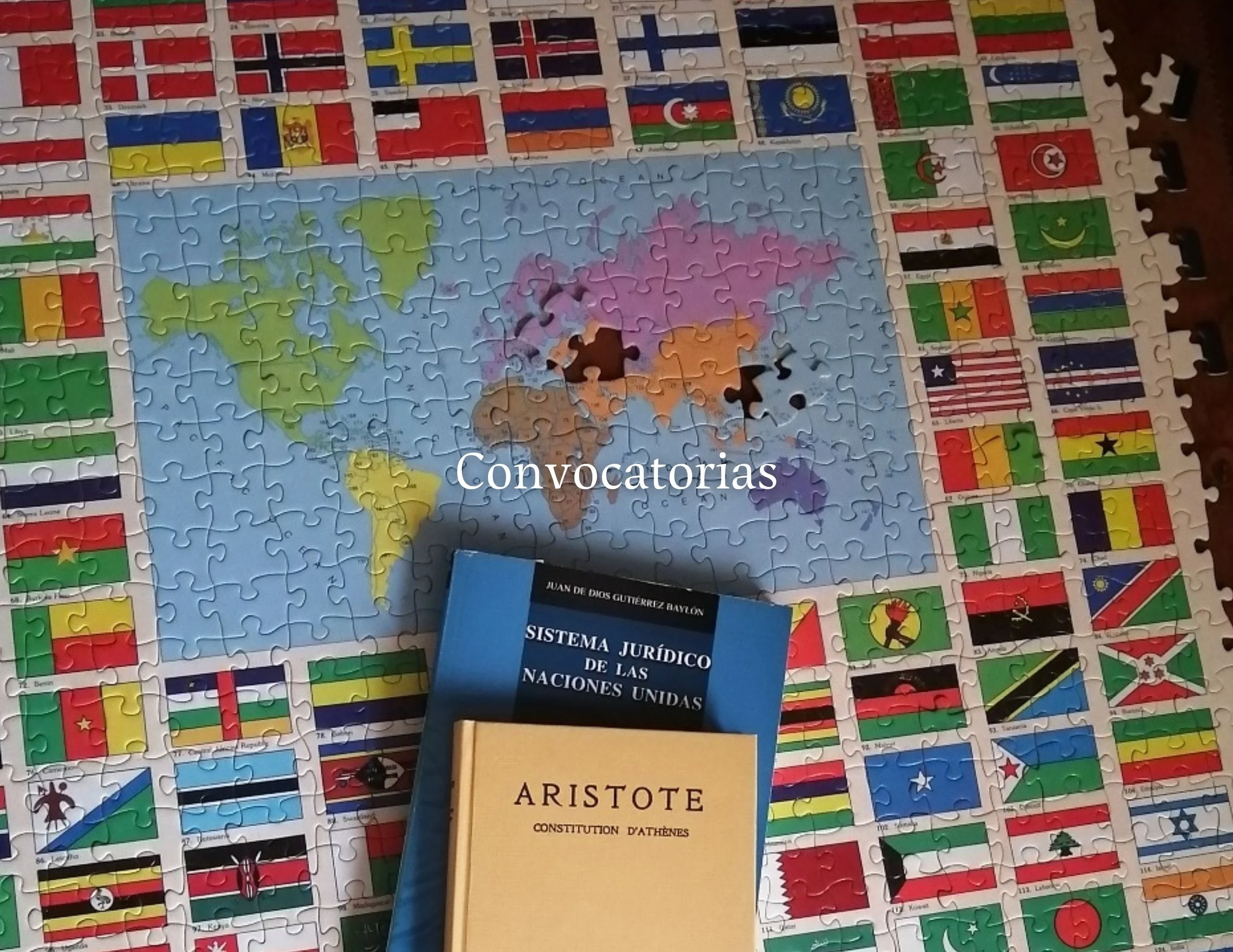 Un rompecabezas con un mapa del mundo y banderas de diferentes países rodeando la imagen. En el centro, hay un libro azul que dice "Sistema Jurídico de las Naciones Unidas" y otro libro amarillo con el título "Aristóteles". La palabra "Convocatorias"