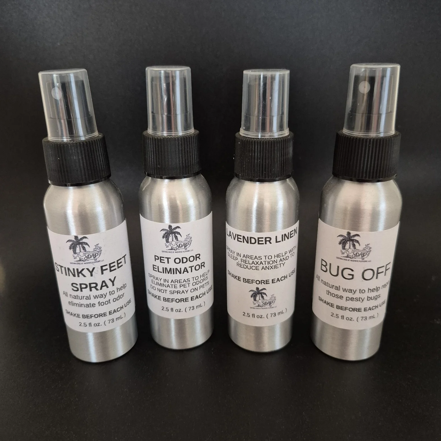 Four small spray bottles with aluminum bodies and black spray nozzles, each labeled with natural pest control solutions such as 'Stinky Feet Spray,' 'Pet Odor Eliminator,' 'Lavender Linen,' and 'Bug Off.'