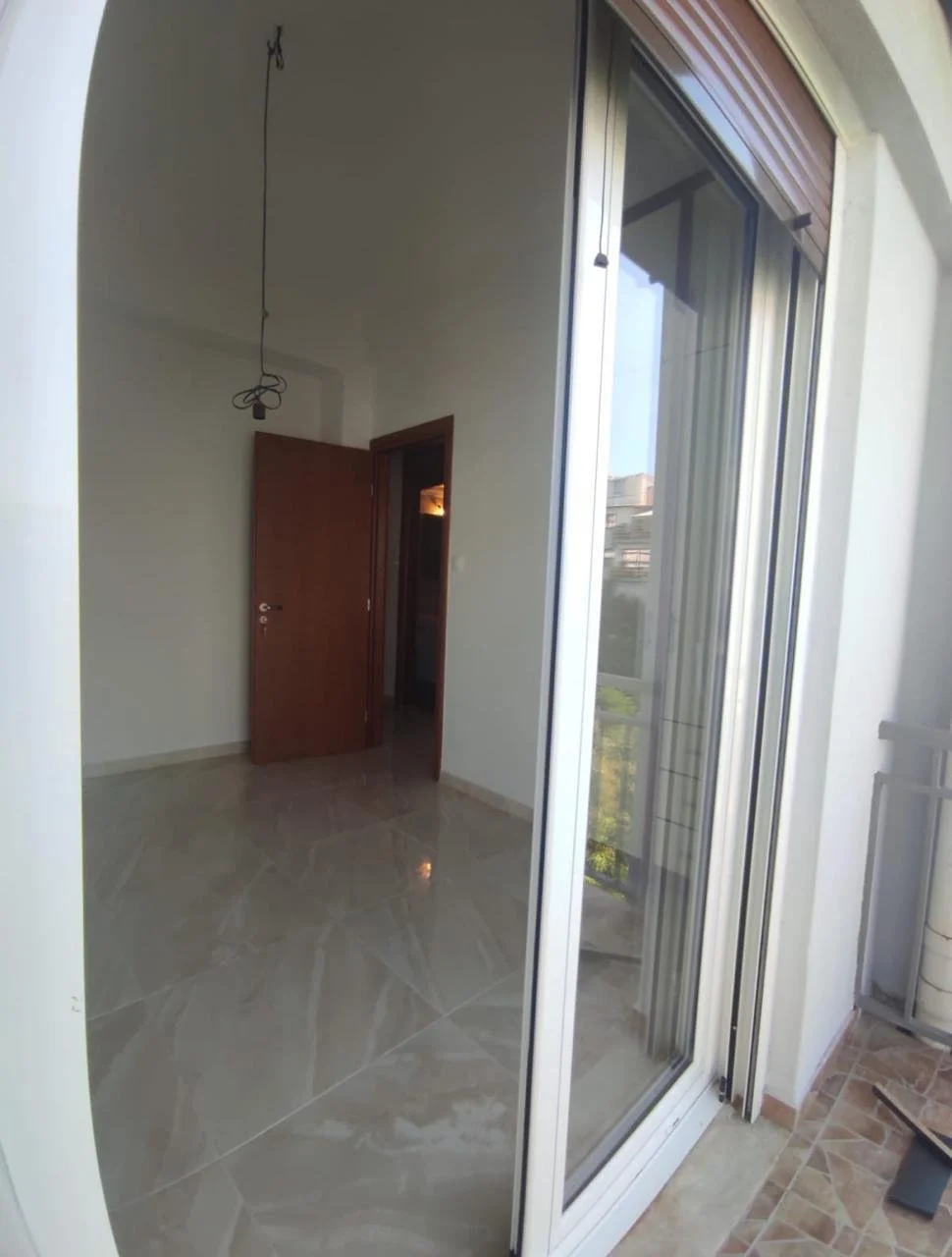 Empty room with open door and sliding glass door leading to outside balcony.