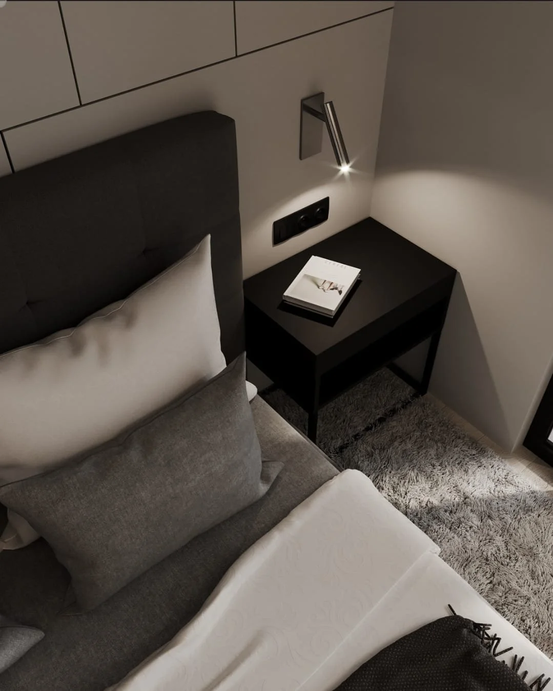 Close-up of a modern bedroom corner with a bed, pillows, nightstand, reading material, wall-mounted light, electrical outlets, and plush rug.