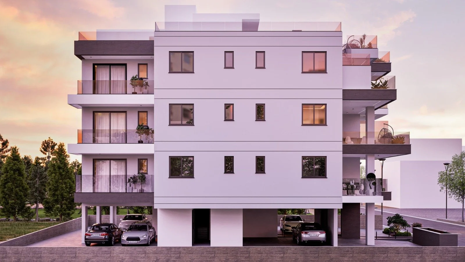 Modern white apartment building with multiple balconies, some with plants, and a parking area with several cars at ground level, set against a sunset sky. Greece, Investment, Golden Visa, Real Estate, Cyprus, Georgia, Lebanon, LPI, Athens.